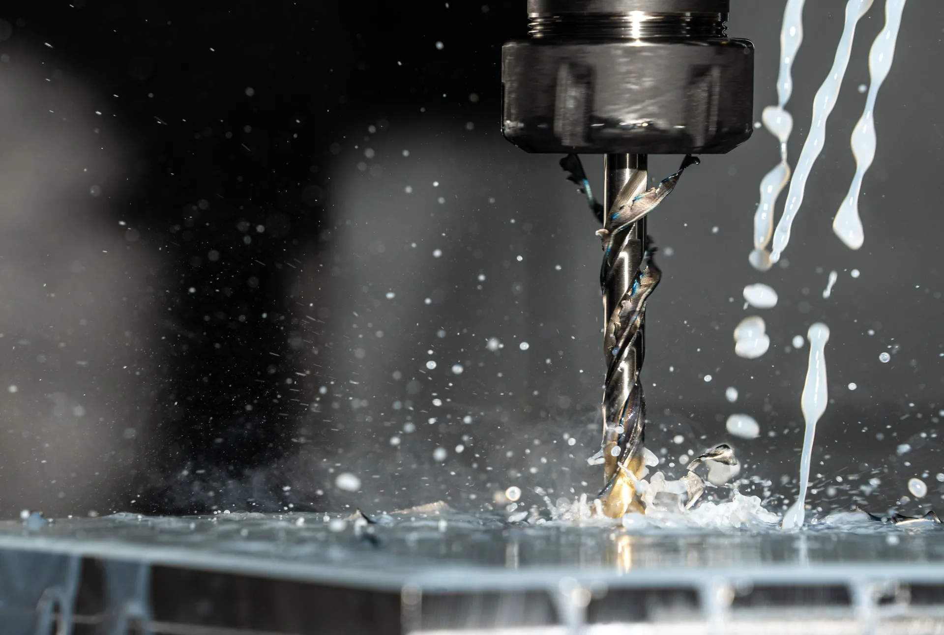 Soğutma sıvısı sıçrarken metal parçayı işleyen CNC matkap ucunun yakın çekimi